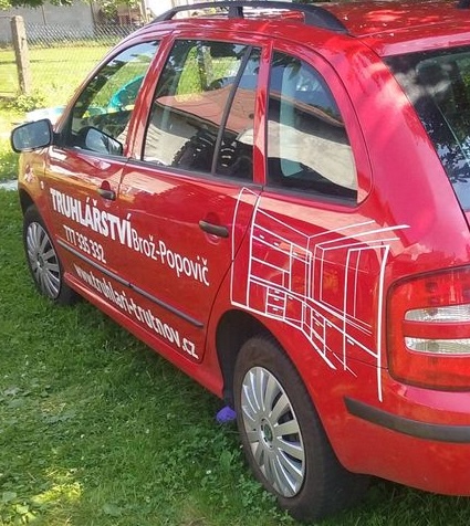 Obrázek červeného auta s polepem truhlářství na boční straně