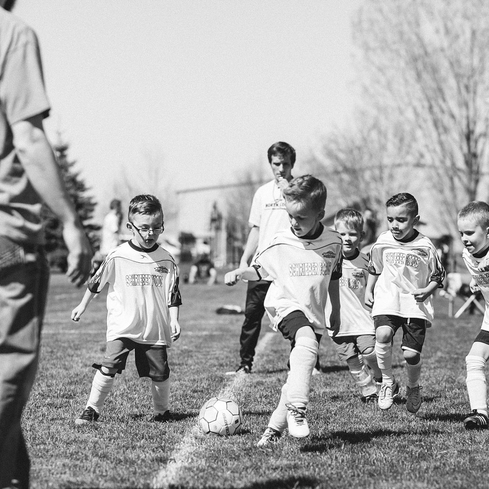 Černobílá fotka dětí hrajících fotbal